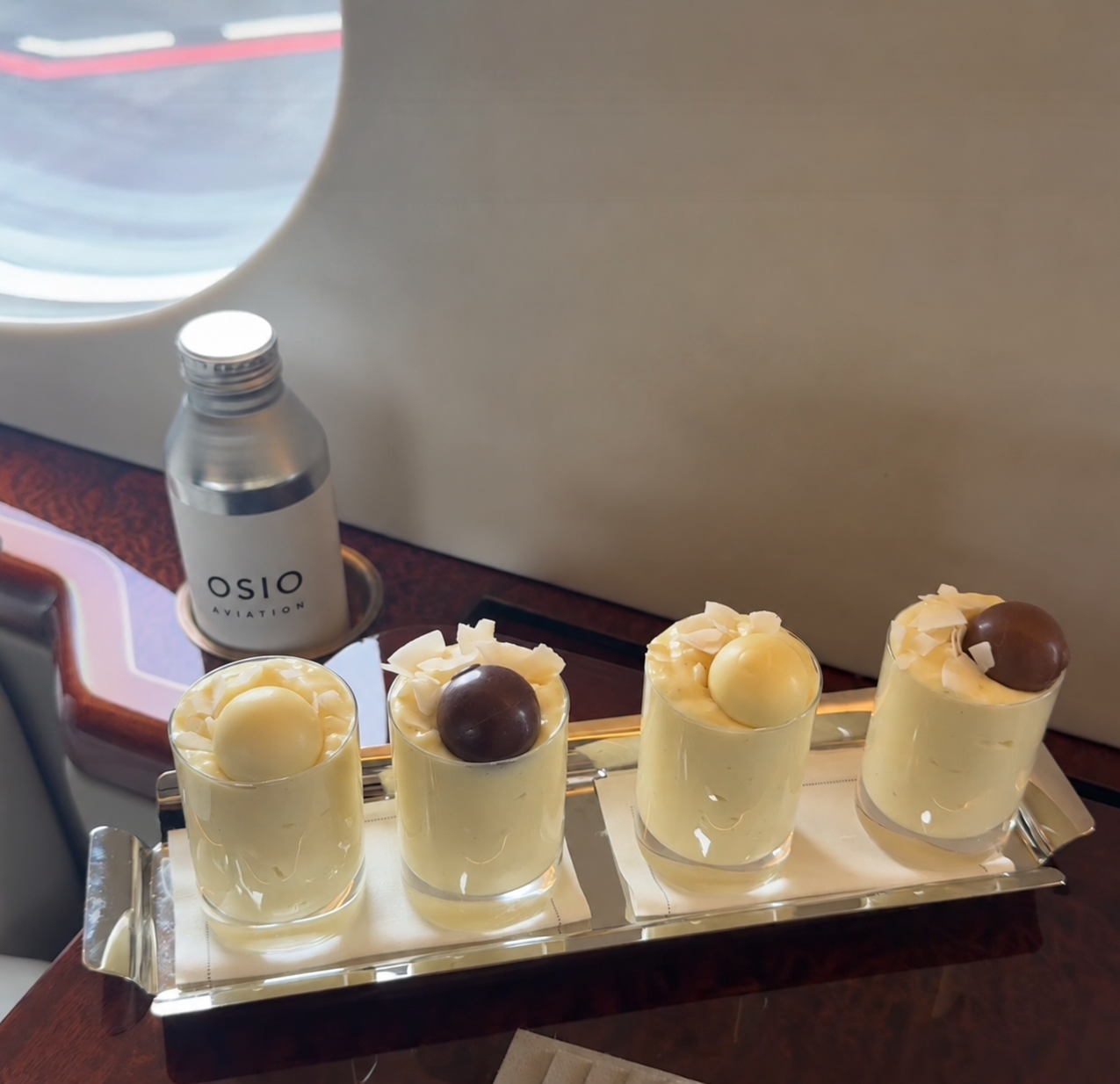 Four petite desserts prepared on board beside an OSIO Aviation branded bottle