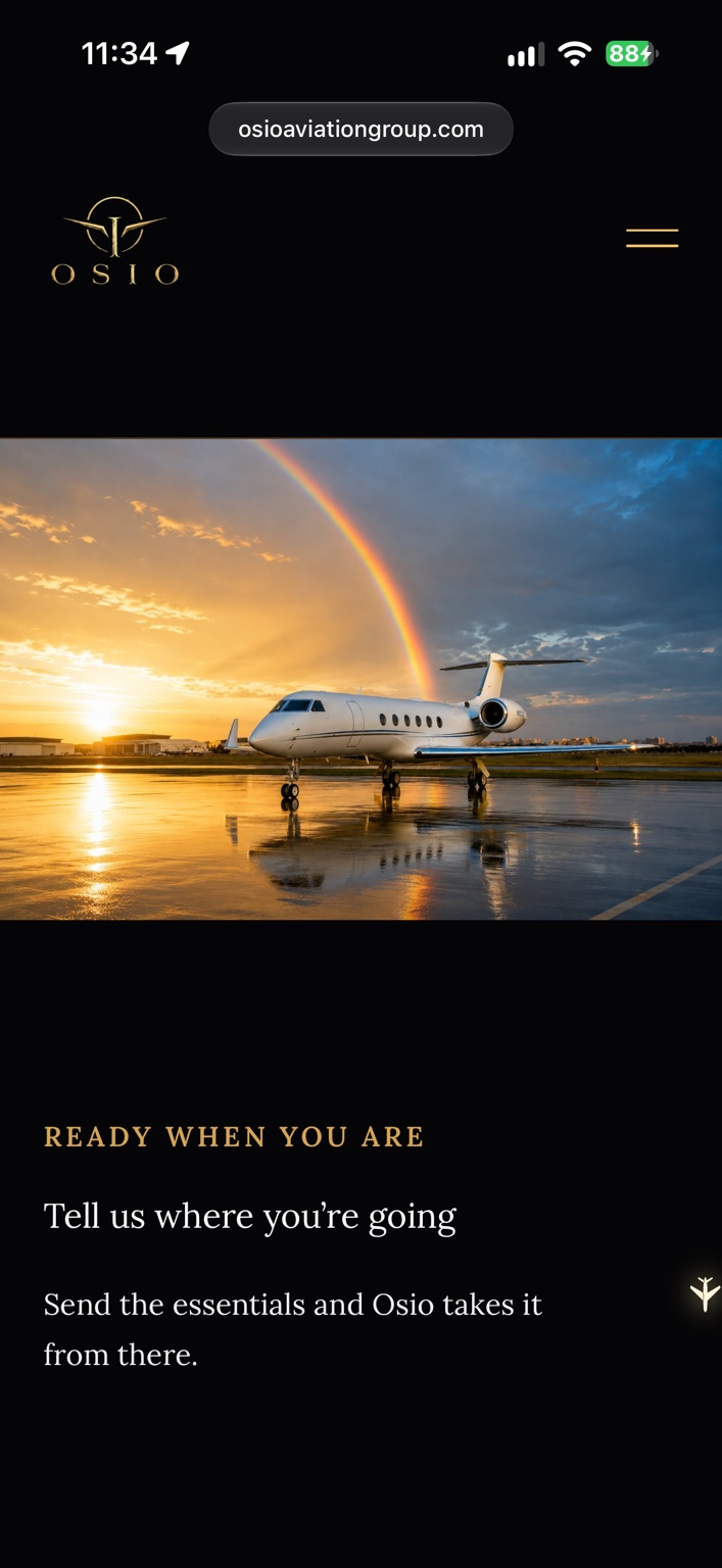 Private jet on a rain-polished apron at sunset beneath a rainbow